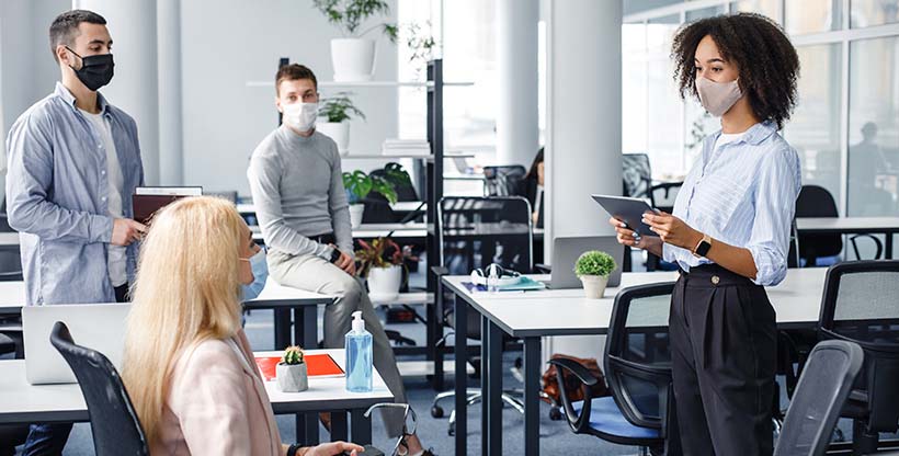 Employees meet safely wearing masks after getting vaccinated and returning to the office.