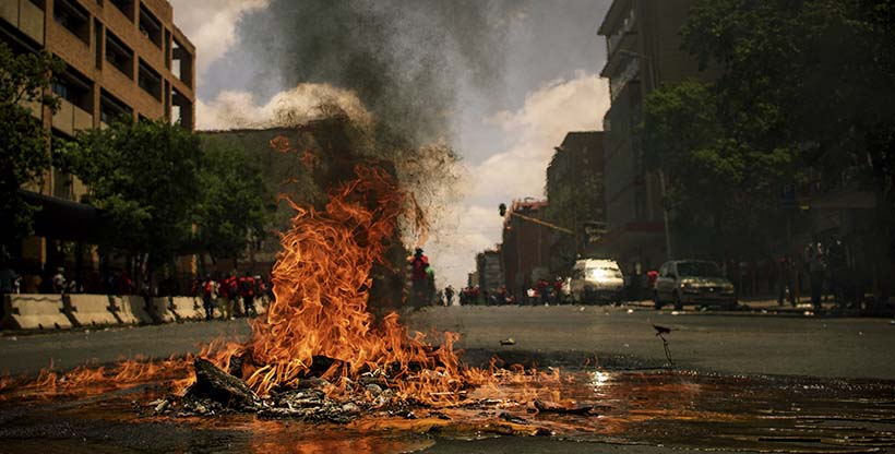 Fire burns in the middle of the street during a riot.