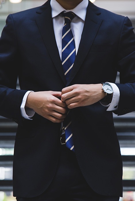 Businessman buttons his suit jacket as he goes down stairs.