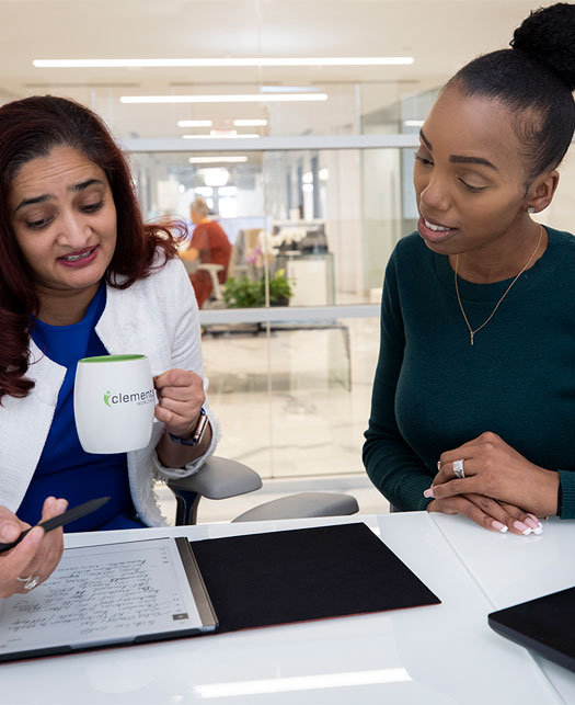 Coworkers review reports during a conversation with coffee.