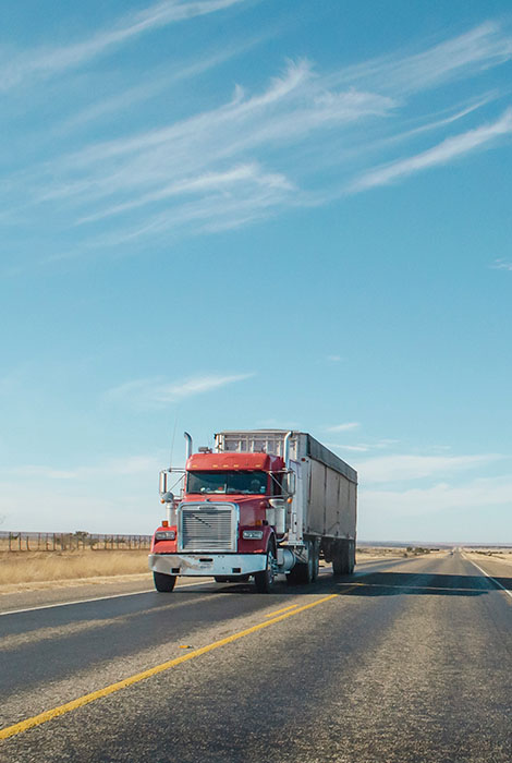 Transfer truck carries large load down country highway.