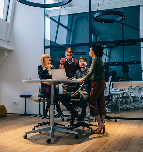 Employees gathers around computer as the discuss work plans.