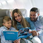 Family of three smile on airplane traveling abroad.