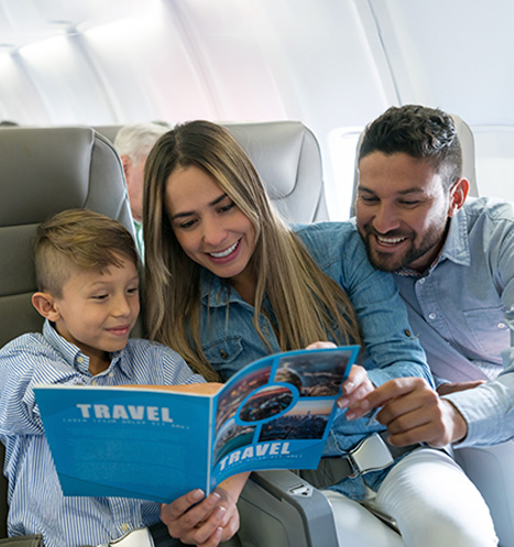 Family of three smile on airplane traveling abroad.