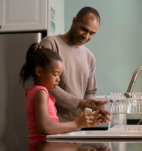 Father and daughter wash hands together to stay healthy.