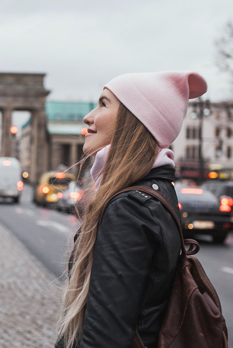 Young woman in front of the Brandenburg Gate in Berlin during early twilight.