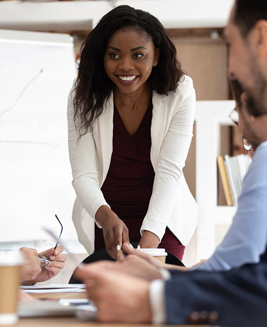 Business woman smiles as she presents to partners during a corporate meeting.