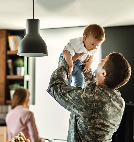 Military father stationed abroad shares a special moment with his baby as he lifts him in the air.