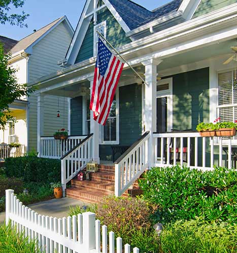 American flag flies on the front porch of a beautiful house in the US.