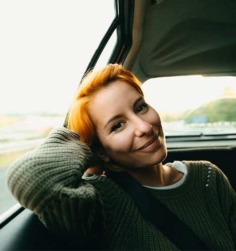 Young expat woman smiling in a car, ready for her next adventure.