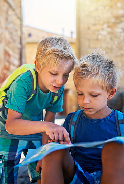 Two young traveler boys ponder over a map to choose their next destination.