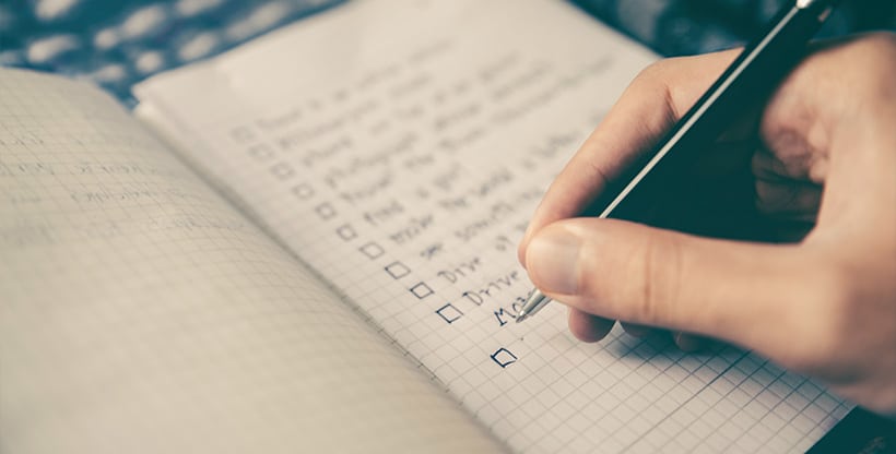 Expat makes a moving to-do list in a notebook with checkboxes preceding each item.