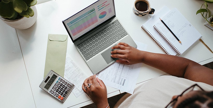 Insurance professional assesses risks using a calculator and a laptop computer. 